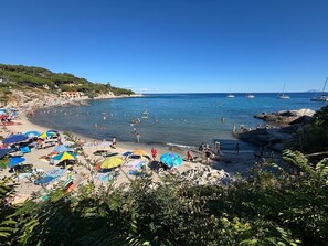 Ein Strand mit Sonnenschirmen, Menschen und Booten.