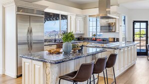 A modern kitchen with a large island, stainless steel appliances, and a view of the mountains. - Hilltop Estate w/ Tennis Court, Pool, Sauna, Game Room, Theater, Panoramic Views (Temecula)