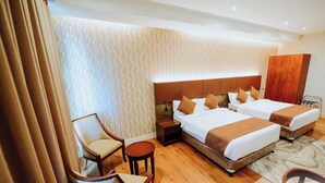 A hotel room with two beds, a chair, a small table, a wardrobe, and a patterned wall. - Hotel La Vista (San Jose del Monte)