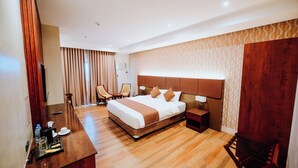 A hotel room with a large bed, a desk with a chair, a small table, and a wardrobe. - Hotel La Vista (San Jose del Monte)