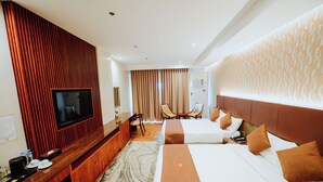 A hotel room with a TV, two beds, a desk with a coffee maker, and a patterned rug. - Hotel La Vista (San Jose del Monte)