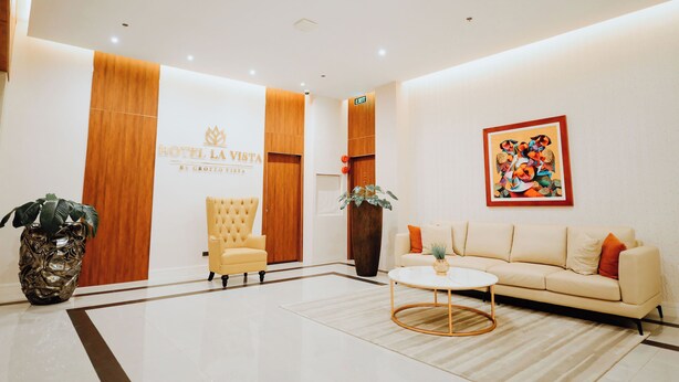 A hotel lobby with a reception desk, a sofa, a coffee table, and a large painting on the wall. - Hotel La Vista (San Jose del Monte)