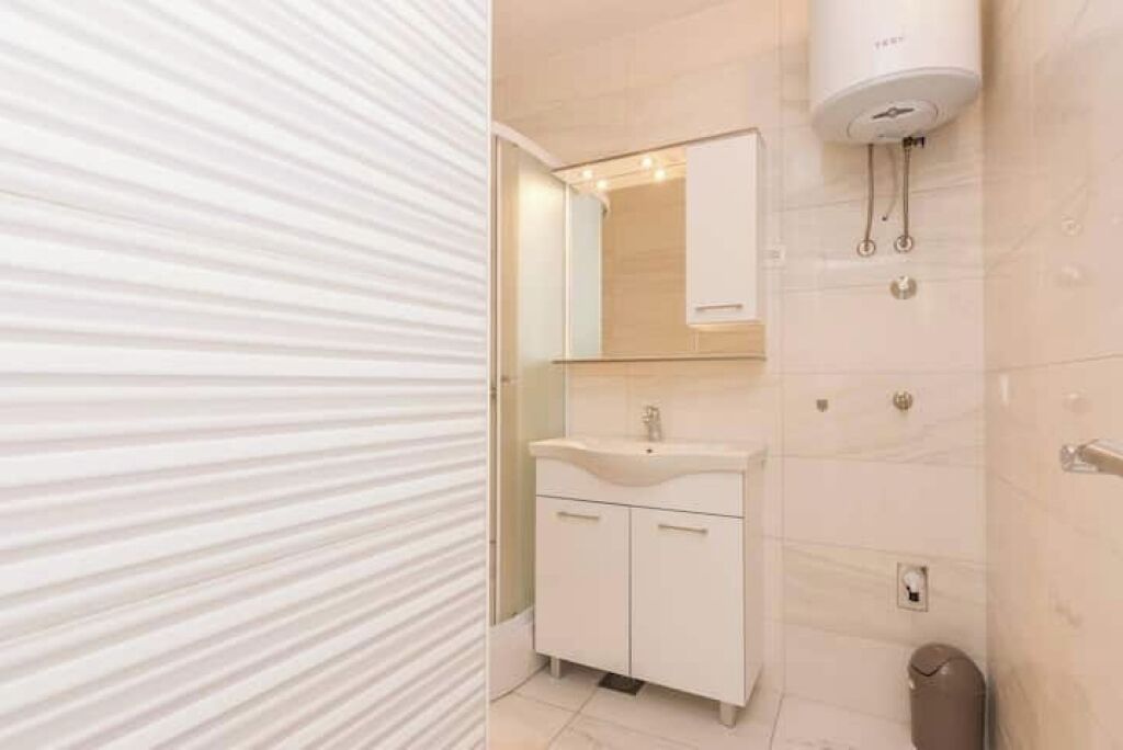 Un baño moderno con lavamanos, espejo y toallero blancos.