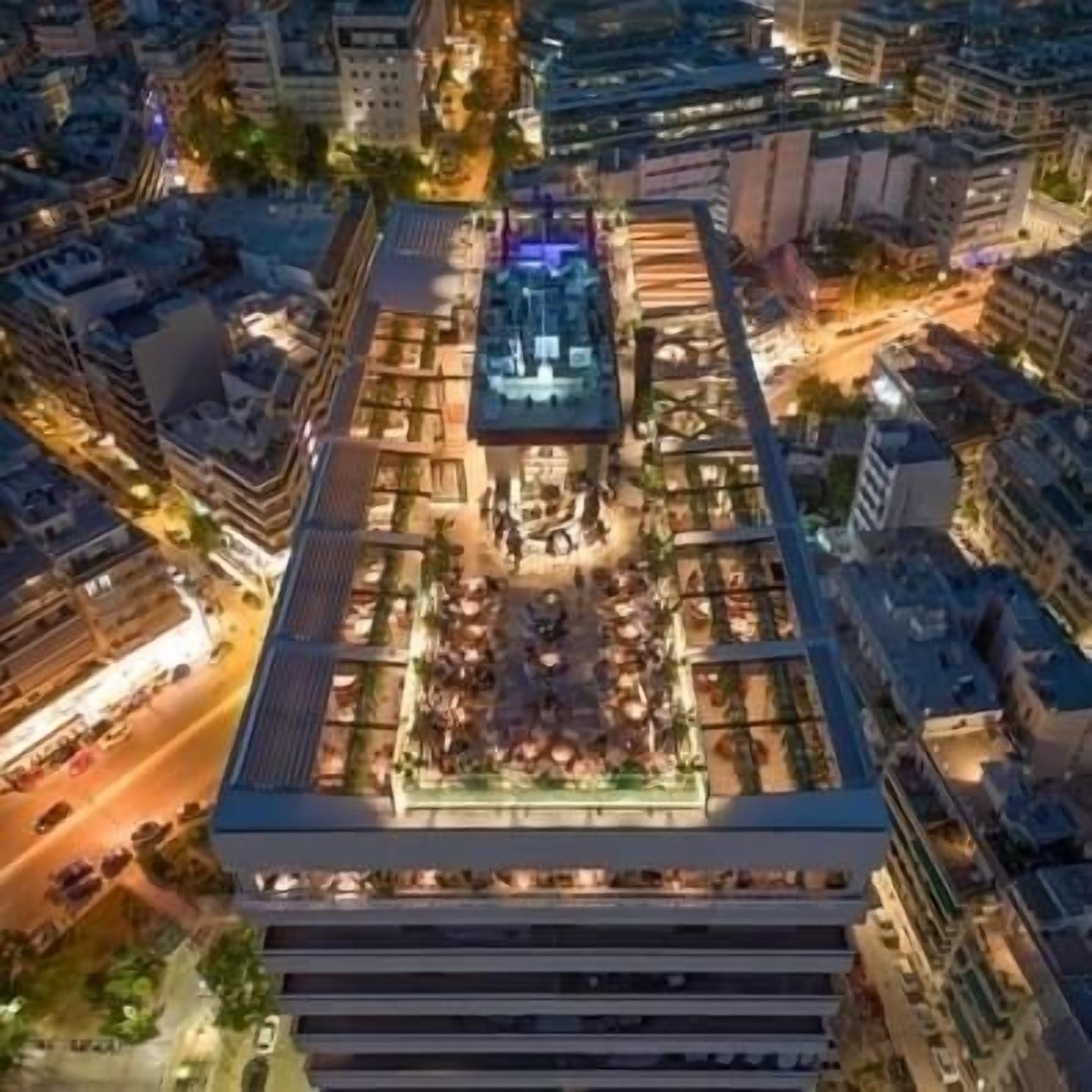 Vue aérienne d’un bâtiment moderne doté d’une terrasse sur le toit, comprenant un espace de détente extérieur et une fontaine centrale.