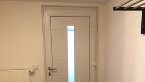 Habitació amb una porta blanca, un radiador, un sòl de fusta i un estri de peu negre.