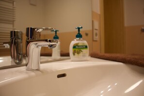 Un lavabo de salle de bain avec un robinet chromé, un miroir et un flacon de savon Palmolive.
