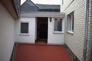 Un étroit sentier menant à l’entrée d’un bâtiment, avec une porte et des fenêtres.