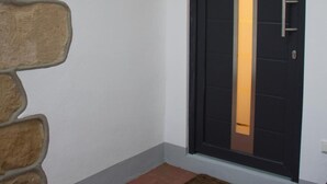 Un interior modern amb una porta negra, un element decoratiu de pared de pedra i un felpó.