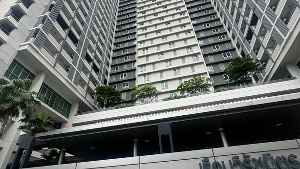Een modern hoog gebouw met een opvallend 'CU HOUSE INTERNATIONAL' bord aan de voet.