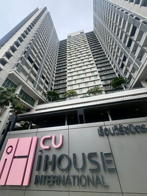Un moderno edificio de gran altura con un llamativo letrero que dice 'CU HOUSE INTERNATIONAL' en la base.