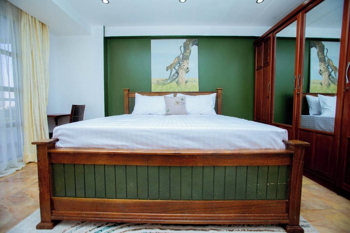 A bedroom with a wooden bed, green walls, and a large mirror.