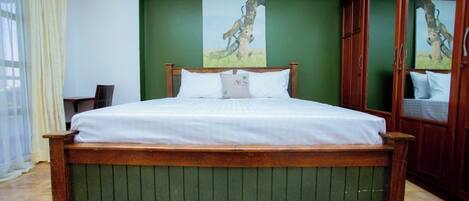Un dormitorio con una cama de madera, paredes verdes y un espejo grande.
