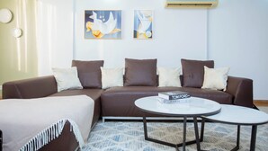 Ein modernes Wohnzimmer mit einem braunen Sofa, weißen und braunen Kissen, einem weißen Couchtisch und zwei gerahmten Kunstwerken an der Wand.