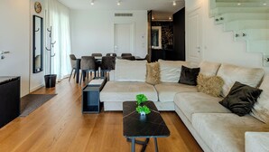 A modern living room with a sofa, a coffee table, and a dining area with chairs and a table. - Villa MaLia Private Pool by Interhome (Costermano Sul Garda)