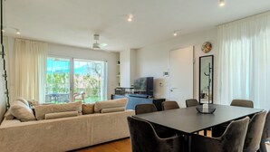 A modern living room with a sofa, dining table, chairs, a TV, and a view of the outdoors. - Villa MaLia Private Pool by Interhome (Costermano Sul Garda)