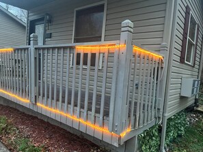 Een houten terras met een balustrade, omringd door een bloembed met mulch en planten.
