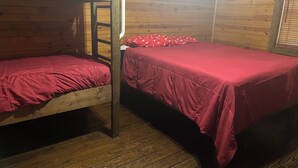 Quarto com beliches de madeira, cada um com roupa de cama vermelha.