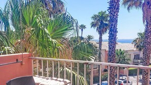 A balcony with a table set for tea, surrounded by palm trees and a view of the sea. - Villa Botrel by Interhome (Sainte Maxime)