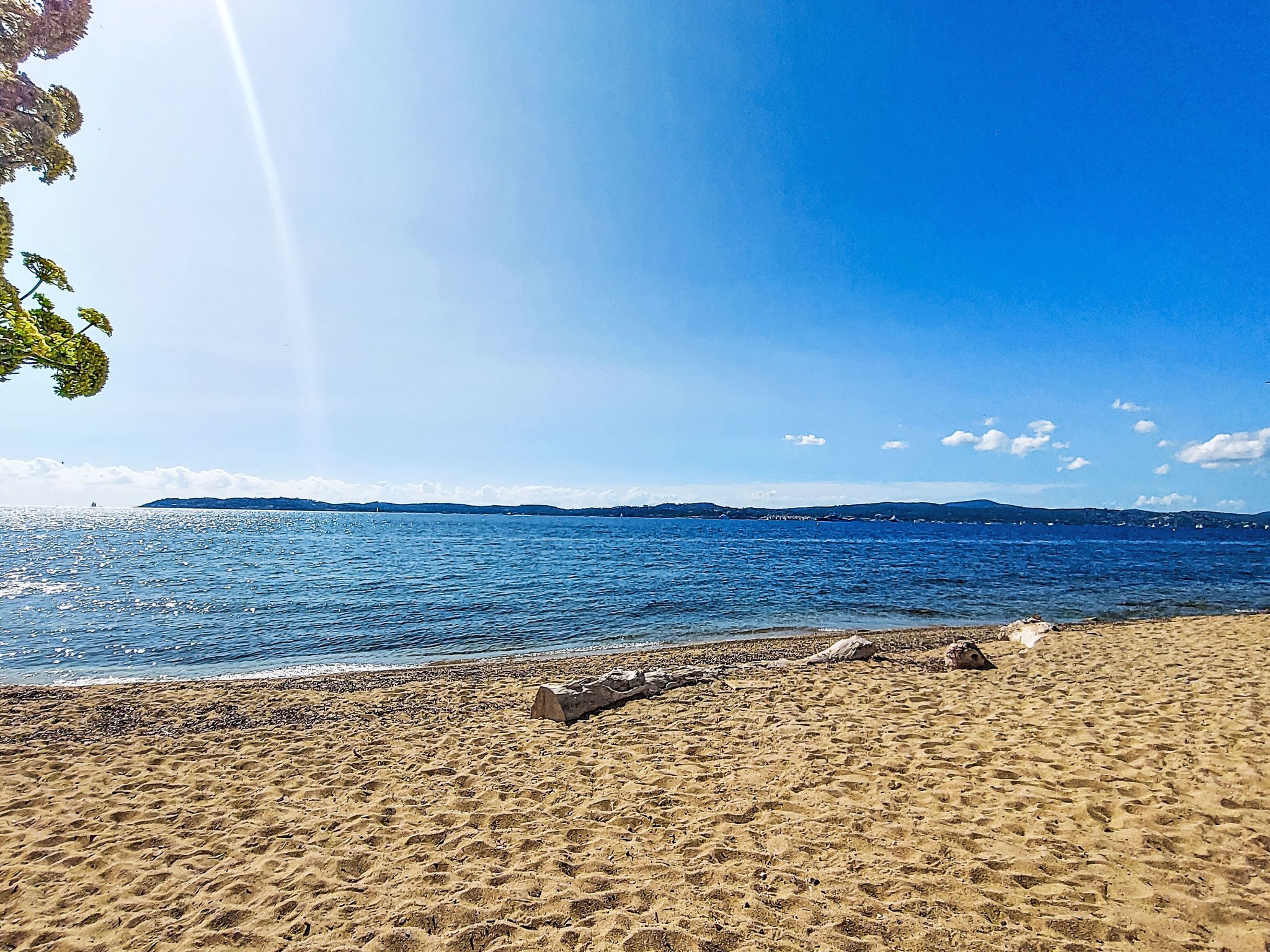 A sandy beach with a clear blue sky and calm sea.