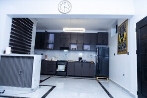 A modern kitchen with dark cabinets, a stainless steel refrigerator, and a clock on the wall.