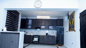 A modern kitchen with dark cabinets, a built-in oven, and a large clock on the wall. - Exclusive 4BR/3BA Penthouse Lux Apartment + Rooftop @ BBB Nation Oasis in Kigali (Kigali)
