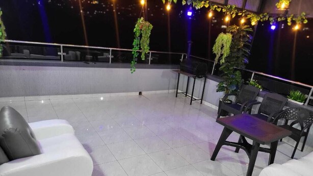 A rooftop terrace with white sofas, a small table, and hanging plants. - Exclusive 4BR/3BA Penthouse Lux Apartment + Rooftop @ BBB Nation Oasis in Kigali (Kigali)