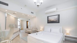 Une chambre d’hôtel moderne, dotée d’un grand lit, d’un bureau, d’une chaise et d’une salle de bain avec un miroir et des rideaux.