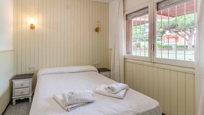 Ein ordentlich bezogenes Bett mit weißen Leinen und Handtüchern, ein Nachttisch und ein Fenster mit Blick auf Gr ün.
