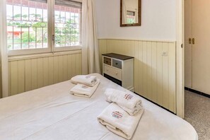 Een hotelkamer met een bed, nachtkastje, spiegel en raam met gordijnen.