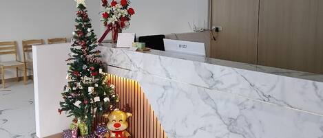 Una moderna zona de recepción con mostrador de mármol, un árbol de Navidad y un mullido juguete de reno.