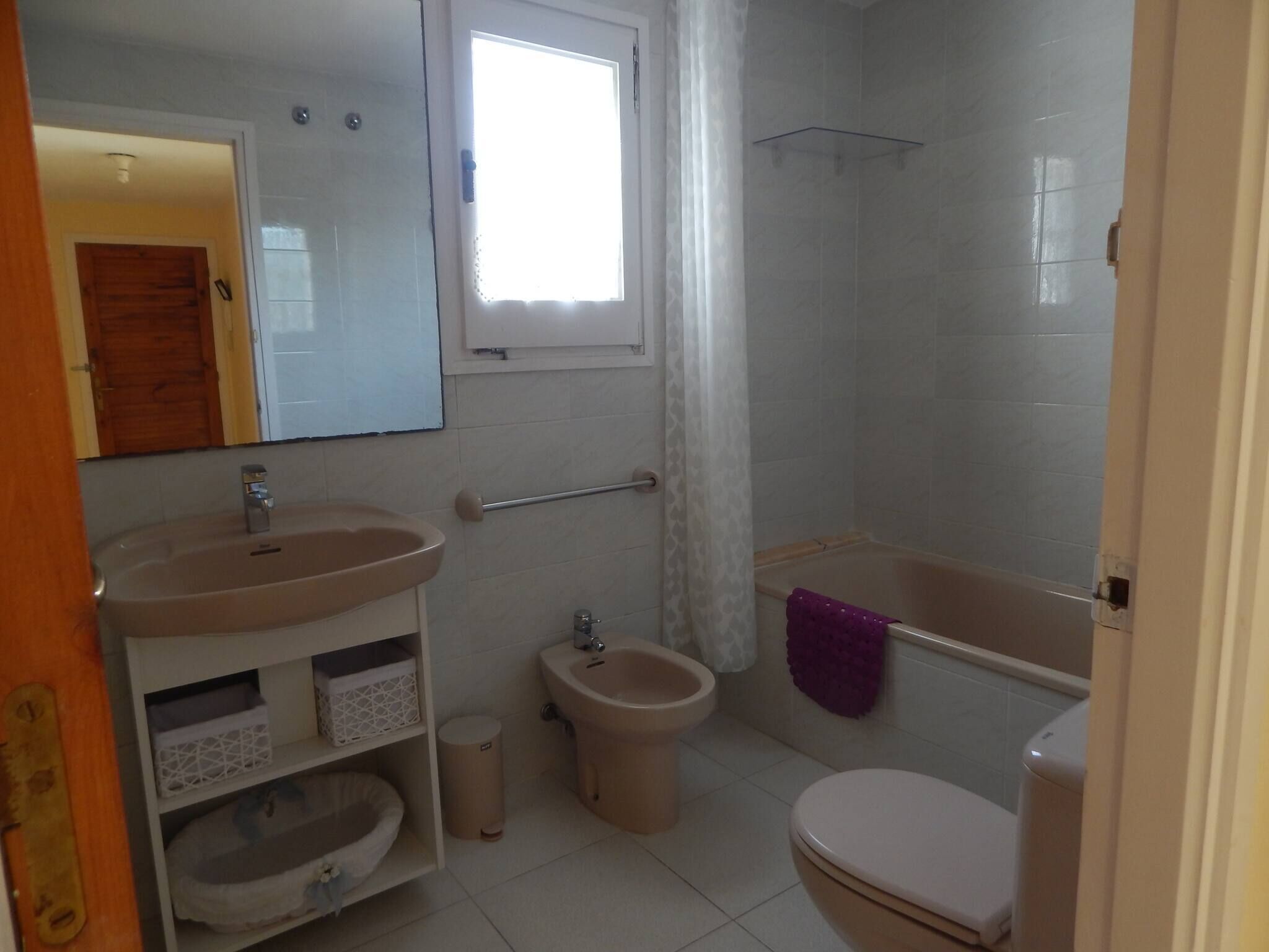 A bathroom with a sink, toilet, bidet, and a shower area.