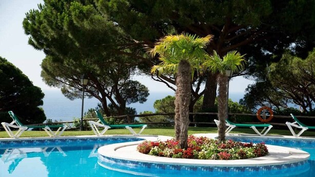 Ein Pool mit einer kreisrunden Insel, umgeben von Liegestühlen und einem Rettungsring.