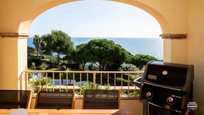 Ein Balkon mit Meerblick, einem Grill und Sitzgelegenheiten im Freien.