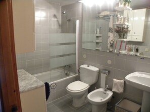 Et badeværelse med bruser, toilet, bidet og håndvask.