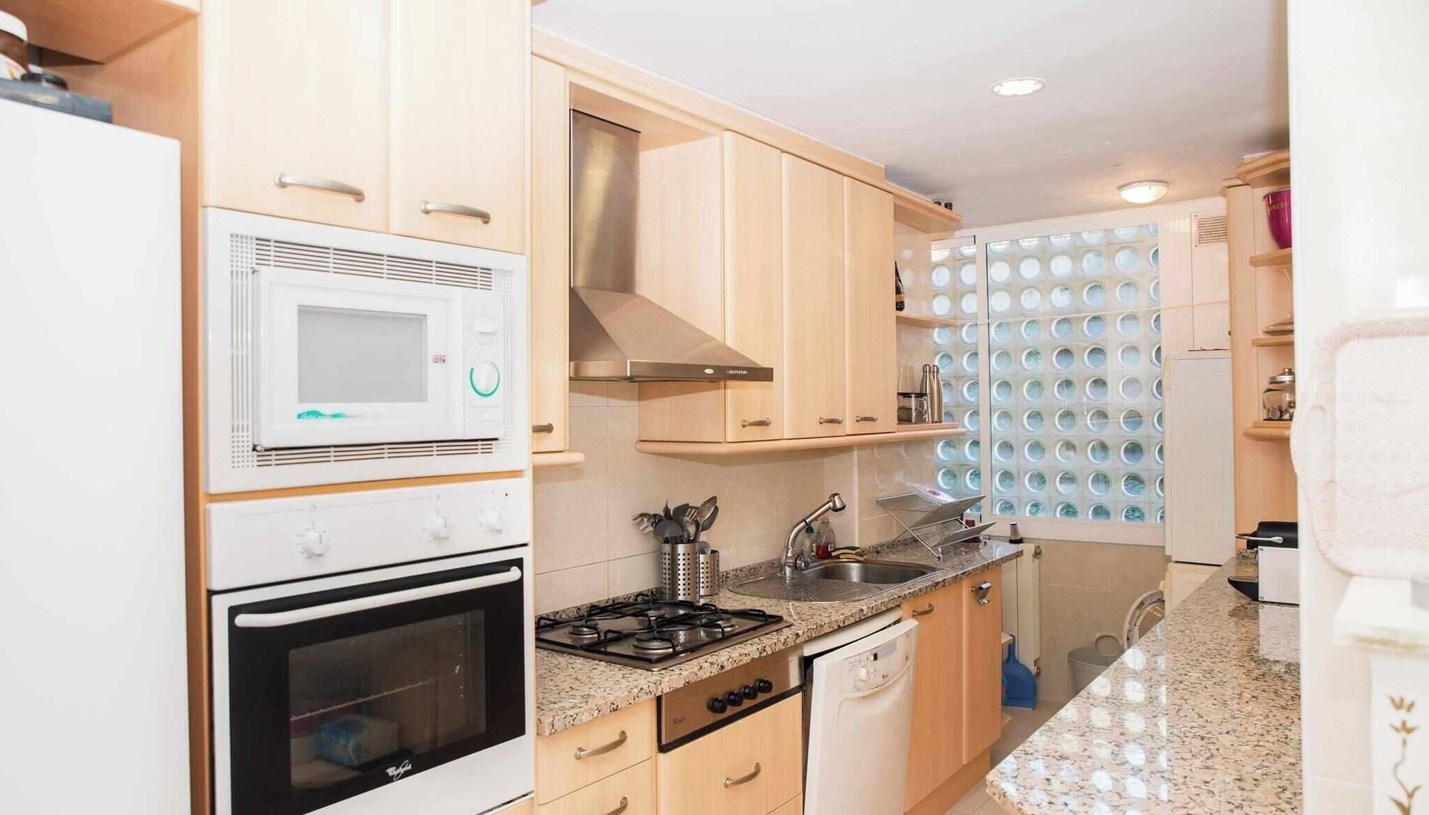 A compact kitchen with a microwave, oven, stove, and sink.