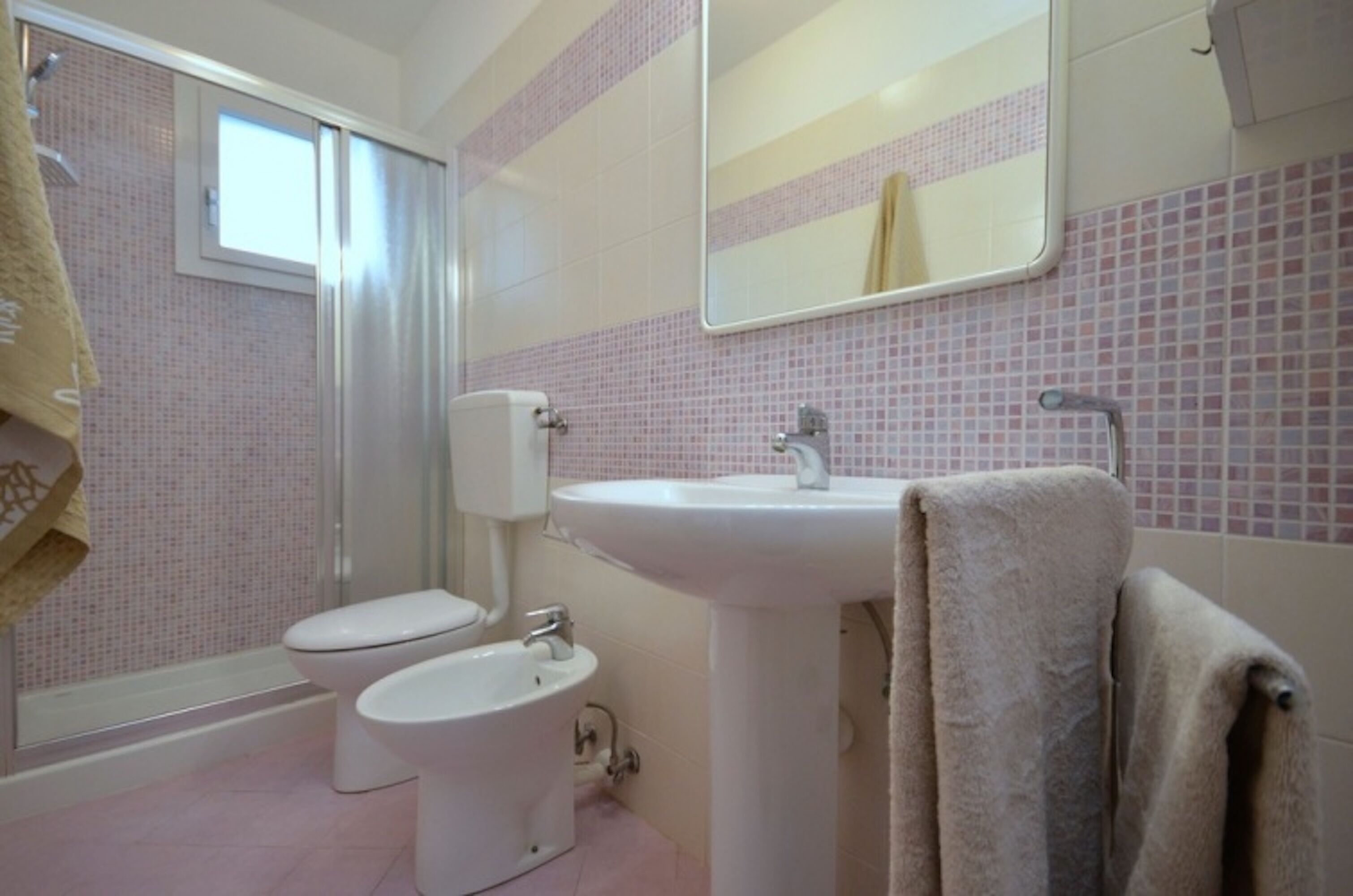 Une salle de bain comprenant des toilettes, un bidet, un lavabo et un espace douche.