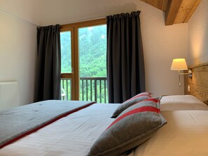 A hotel room with two beds, a view of greenery through the window, and a bedside lamp. - 4-person apartment in Pelvoux! 67m2, mountain view Résidence Le Glacier Blanc (Vallouise-Pelvoux)