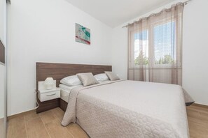A bedroom with a bed, nightstand, and window with curtains. - Villa Star 1 (Novalja)
