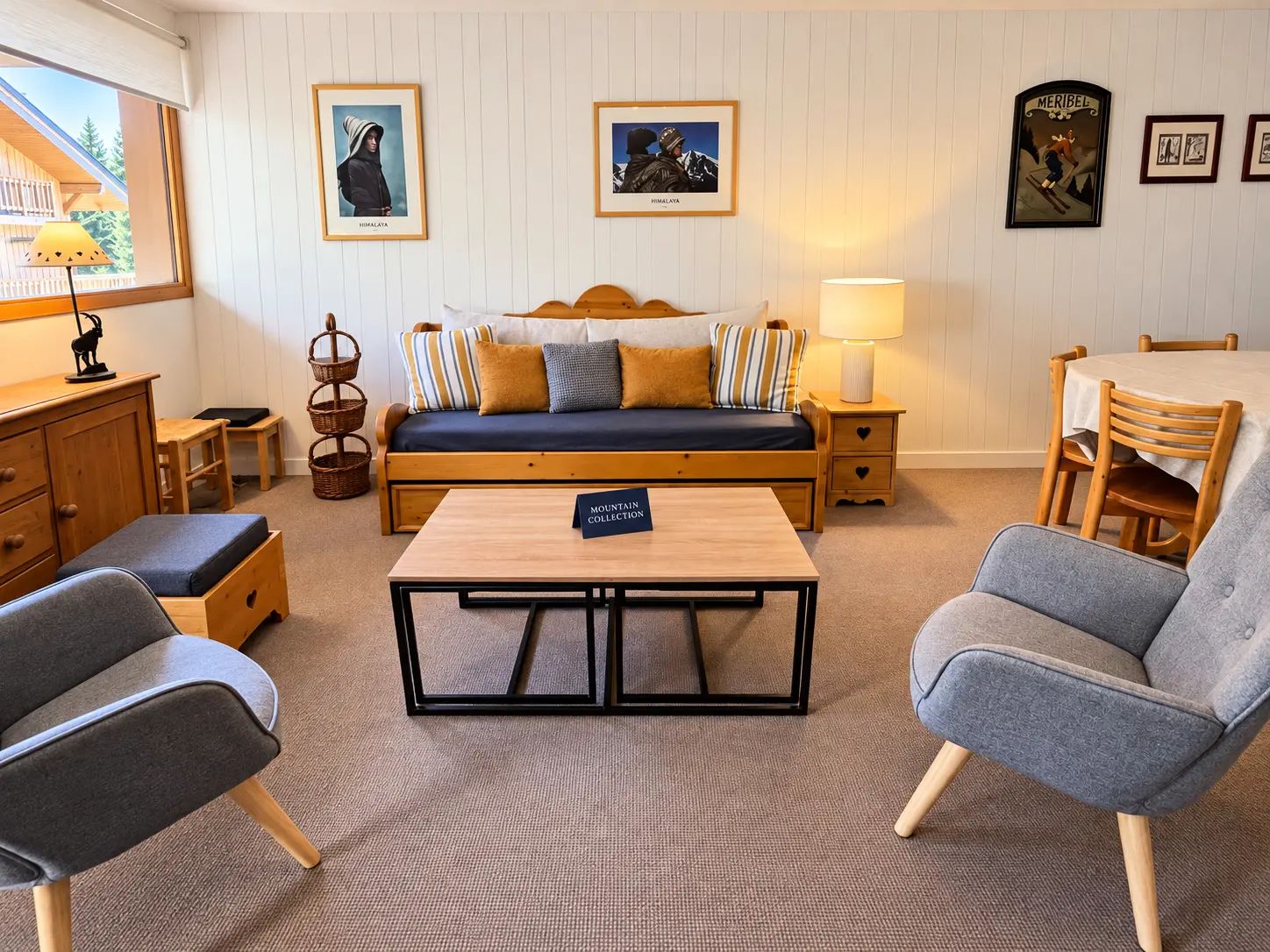 A cozy room with a bed, a table, two chairs, a lamp, and framed pictures on the wall.