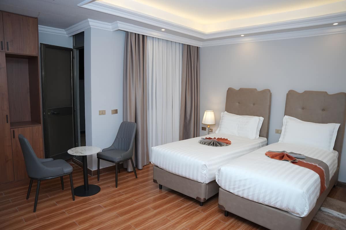 Una habitación de hotel con dos camas, un escritorio, una silla y un armario.