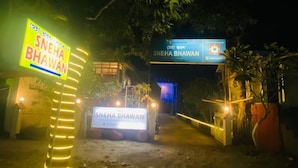 Een bord voor SNEHA BHAWAN, 's nachts verlicht.