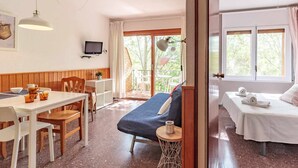 Ein Zimmer mit einem Bett, einem Schreibtisch, einem Stuhl, einem Tisch mit Tassen und einem Fernseher an der Wand.