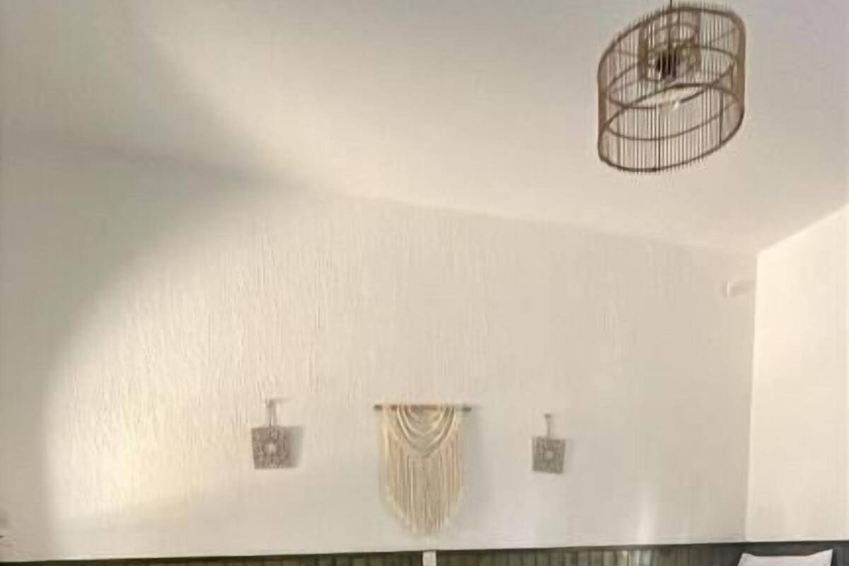 Una camera d'albergo con due letti singoli, un tavolino e una lampada a sospensione.