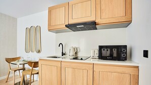 A compact kitchen with wooden cabinets, a black range hood, a coffee maker, a toaster, and a microwave.