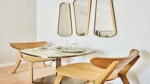 A dining area with a round table, wooden chairs, and three wall-mounted mirrors.