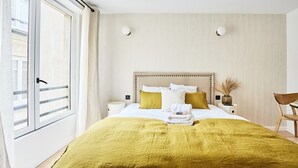 A hotel room with a large bed, a bedside table, a chair, and a window with a view.
