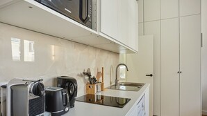 Een kleine keuken met een koffiezetapparaat, broodrooster en een spoelbak.