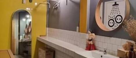 A bathroom with a white sink, a mirror, and a shower area.