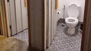 Un couloir étroit, dont le sol est recouvert de carreaux, mène à une salle de bain.