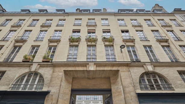 Un edificio de varios pisos con fachada simétrica, ventanas amplias y una entrada central.